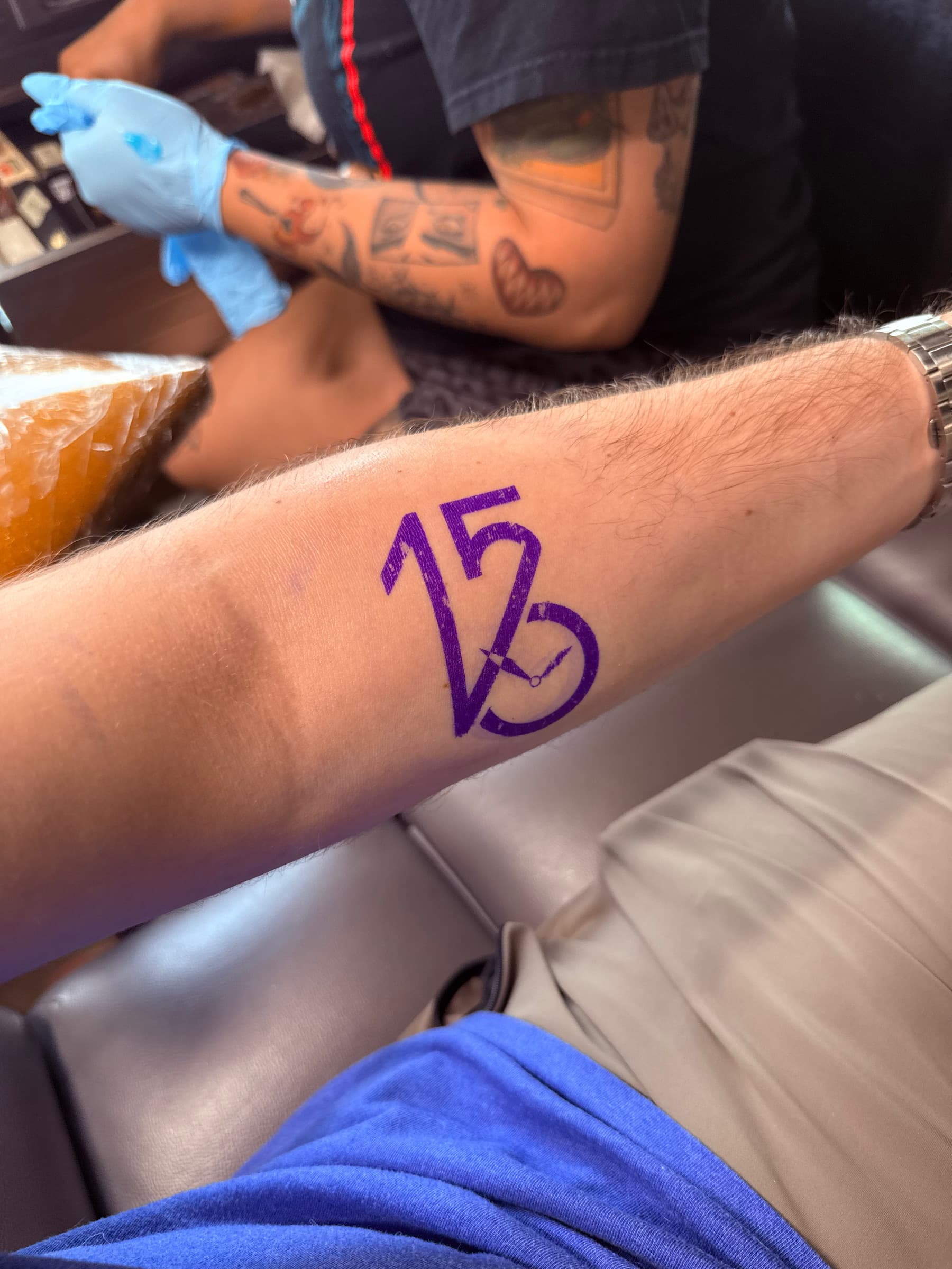 Purple stencil of the tattoo aligned on the inner forearm before the needle work begins.