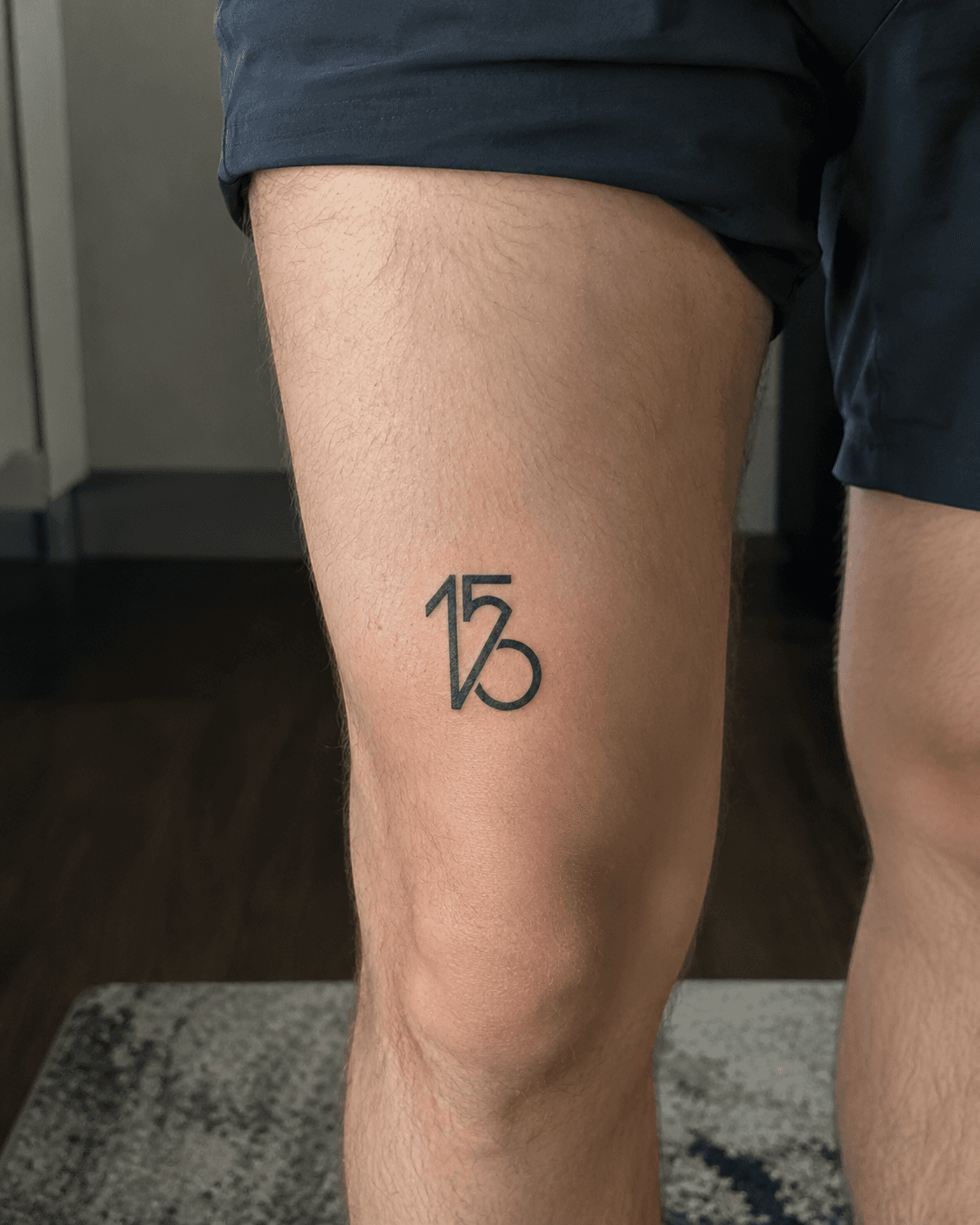 The 156 / watch monogram inked above the knee on a thigh.